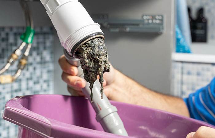 The plumber removes the blockage in the pipes, disassembles the siphon, pulls out the dirt.
