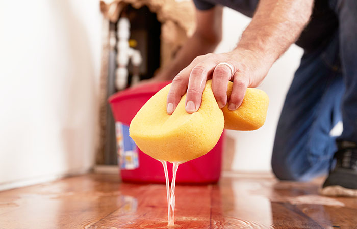 Man mopping up water from the floor with a sponge, detail